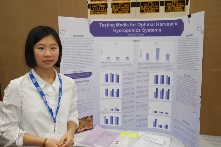 Angela Yuan, AAST junior, in front of her research poster on agriculture. 